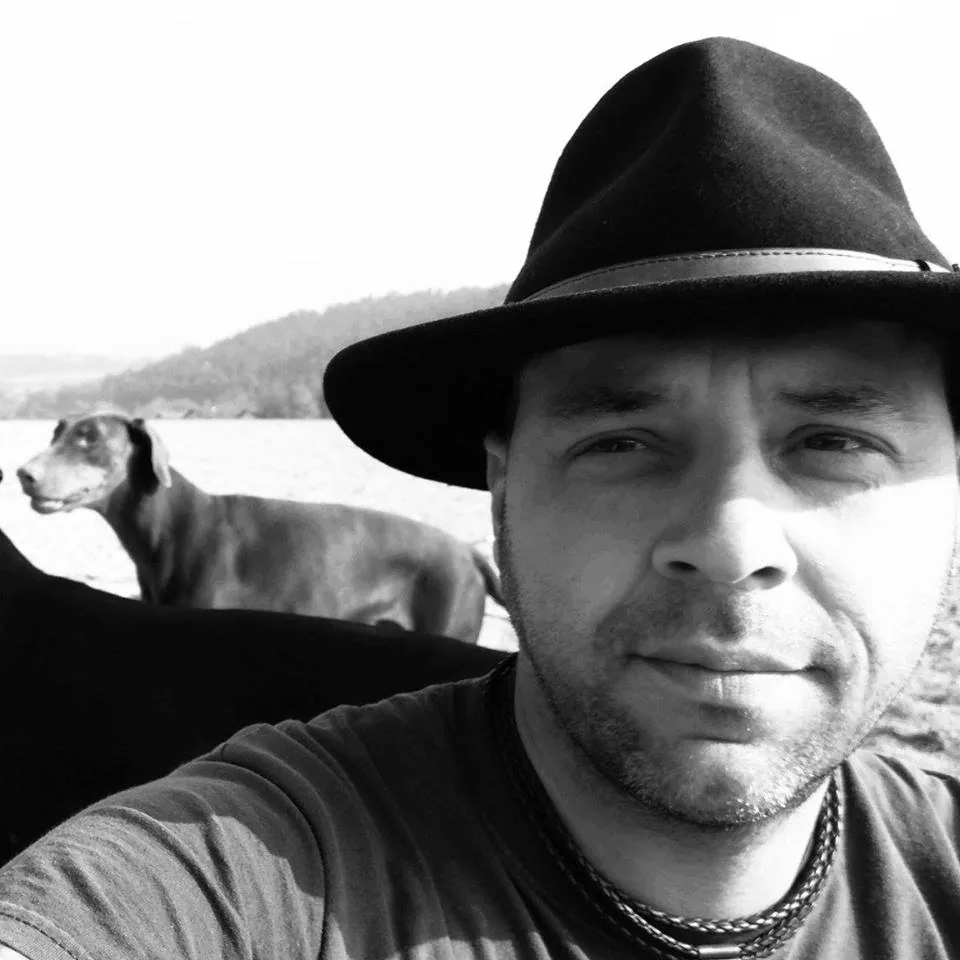 Christian Huber mit Hut und seinem Hund im Hintergrund